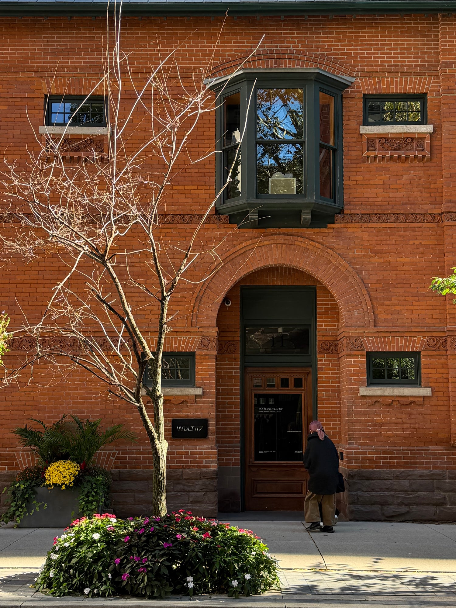 WDLT117 Toronto storefront at 7 St. Thomas Street, with red brick architecture and flowers outside the entrance.